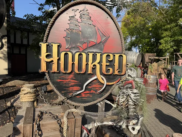 Hooked scare zone sign at Kings Island: a painted pirate ship medallion surrounded by rope, chains and skeletons